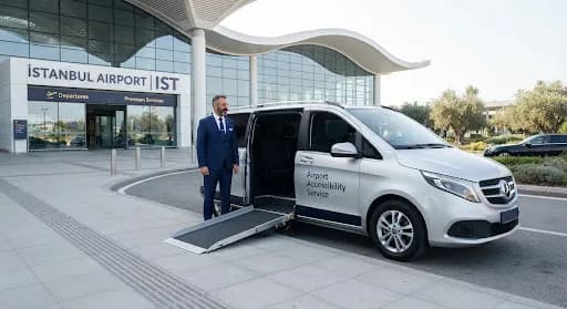 Driver beside a minivan with its wheelchair ramp lowered at the Istanbul Airport entrance